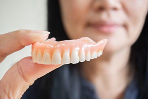 a patient holding her dentures