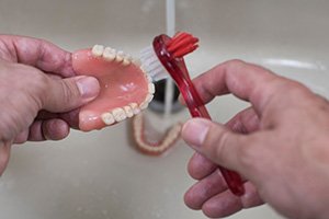a patient brushing their dentures