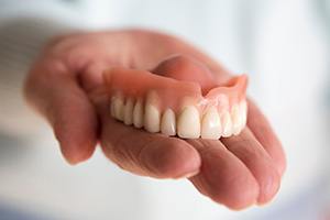 a person holding their dentures