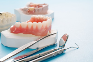 Model dentures sitting next to several dental tools